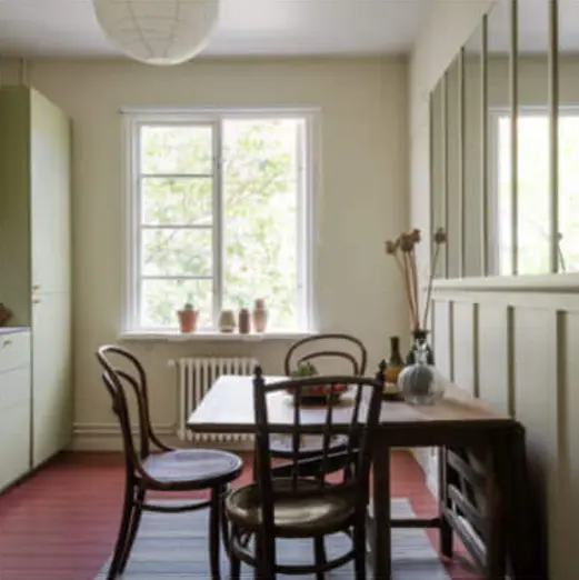 Bright apartment room with dining table, wooden chairs and windows