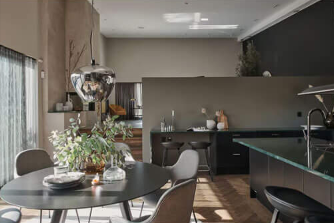 Modern dining area with black table, designer chairs and dark kitchen